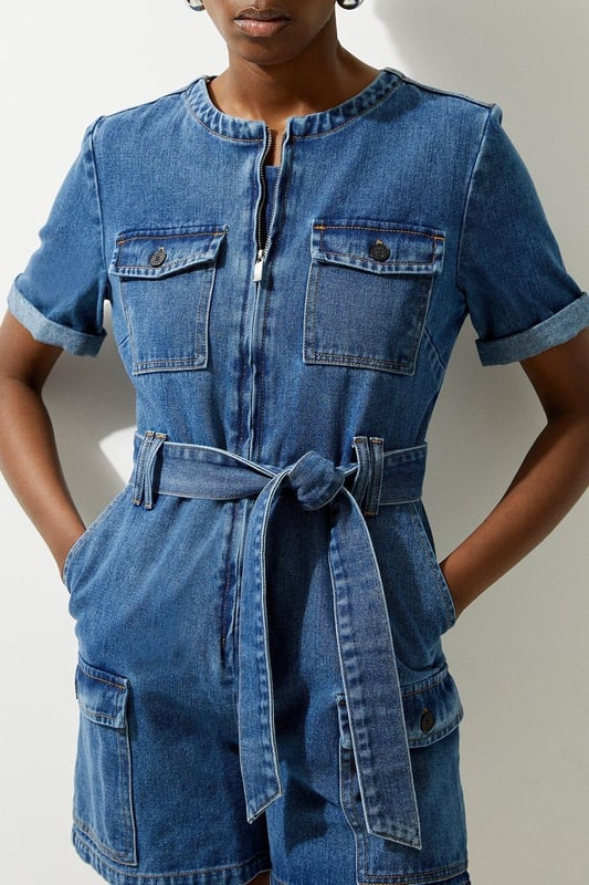 Elevate your summer wardrobe in our playsuit, with high quality denim fabric, featuring a belted waistline, as well as a utility design and relaxed fit shorts. Styles well with trainers or sandals for a summer outfit that can be worn again and again. Denim Cargo Pocket Belted Playsuit High Quality Denim Fabric Flattering Relaxed Fit Summery Short Sleeves Unique Cargo Style Zip Front Fastenings Belted Waist for a Cinched Silhouette
