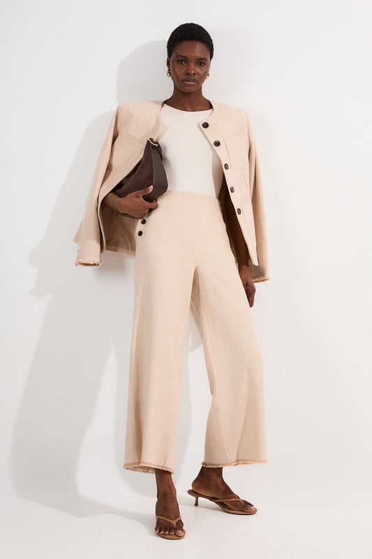These cropped wide-leg trousers create a modern, relaxed shape while the high waistband defines your silhouette. Style with a fitted tank top for daytime sophistication, or pair with a crisp white shirt for a more structured look. The decorative button detailing adds a distinctive touch that reflects Karen Millen's attention to refined details. Perfect for family brunches, or casual workplace settings, these versatile trousers transition effortlessly from day to evening when paired with a silk blouse and strappy sandals. The neutral tone makes them an excellent foundation piece for your wardrobe, working with both bold and subtle colour palettes throughout the seasons.   Tailored wide leg trousers featuring distinctive button detailing Cropped length design High-waisted silhouette Textured tweed fabric  Matching piece sold separately.