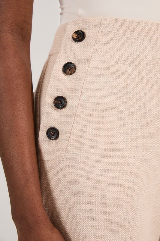 These cropped wide-leg trousers create a modern, relaxed shape while the high waistband defines your silhouette. Style with a fitted tank top for daytime sophistication, or pair with a crisp white shirt for a more structured look. The decorative button detailing adds a distinctive touch that reflects Karen Millen's attention to refined details. Perfect for family brunches, or casual workplace settings, these versatile trousers transition effortlessly from day to evening when paired with a silk blouse and strappy sandals. The neutral tone makes them an excellent foundation piece for your wardrobe, working with both bold and subtle colour palettes throughout the seasons.   Tailored wide leg trousers featuring distinctive button detailing Cropped length design High-waisted silhouette Textured tweed fabric  Matching piece sold separately.