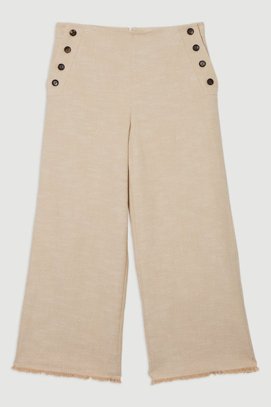 These cropped wide-leg trousers create a modern, relaxed shape while the high waistband defines your silhouette. Style with a fitted tank top for daytime sophistication, or pair with a crisp white shirt for a more structured look. The decorative button detailing adds a distinctive touch that reflects Karen Millen's attention to refined details. Perfect for family brunches, or casual workplace settings, these versatile trousers transition effortlessly from day to evening when paired with a silk blouse and strappy sandals. The neutral tone makes them an excellent foundation piece for your wardrobe, working with both bold and subtle colour palettes throughout the seasons.   Tailored wide leg trousers featuring distinctive button detailing Cropped length design High-waisted silhouette Textured tweed fabric  Matching piece sold separately.