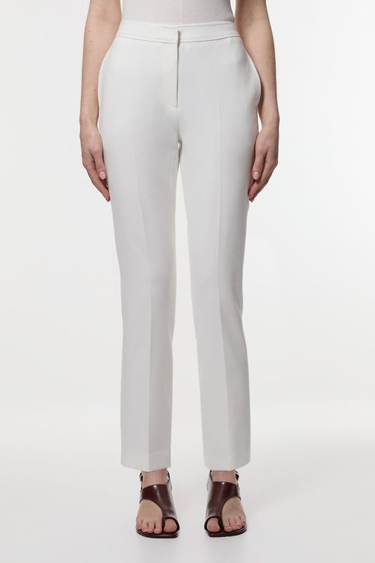 These Karen Millen tailored trousers combine professional polish with modern comfort. The slim leg design creates a refined silhouette that transitions seamlessly from boardroom to evening engagements. Style with a coordinating blazer and pointed flats for a sophisticated workwear ensemble, as shown by our model, or pair with a crisp white shirt and block heels for client meetings. The stretch-enhanced fabric allows for comfortable movement whilst maintaining structure, ideal for long days at the office. For after-work occasions, simply add statement jewellery and swap flats for elegant heels. These versatile trousers form the foundation of a capsule workwear wardrobe, offering endless styling possibilities whilst maintaining a distinctly professional appearance. Their timeless design ensures they'll remain a wardrobe staple for seasons to come.  Tailored slim leg design with clean, streamlined silhouette Stretch fabric blend for exceptional comfort and movement Sleek waistband with subtle front closure Versatile 60cm length perfect for pairing with flats or heels Sophisticated straight-leg cut that maintains its shape throughout the day  Matching piece sold separately.
