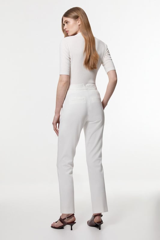 These Karen Millen tailored trousers combine professional polish with modern comfort. The slim leg design creates a refined silhouette that transitions seamlessly from boardroom to evening engagements. Style with a coordinating blazer and pointed flats for a sophisticated workwear ensemble, as shown by our model, or pair with a crisp white shirt and block heels for client meetings. The stretch-enhanced fabric allows for comfortable movement whilst maintaining structure, ideal for long days at the office. For after-work occasions, simply add statement jewellery and swap flats for elegant heels. These versatile trousers form the foundation of a capsule workwear wardrobe, offering endless styling possibilities whilst maintaining a distinctly professional appearance. Their timeless design ensures they'll remain a wardrobe staple for seasons to come.  Tailored slim leg design with clean, streamlined silhouette Stretch fabric blend for exceptional comfort and movement Sleek waistband with subtle front closure Versatile 60cm length perfect for pairing with flats or heels Sophisticated straight-leg cut that maintains its shape throughout the day  Matching piece sold separately.