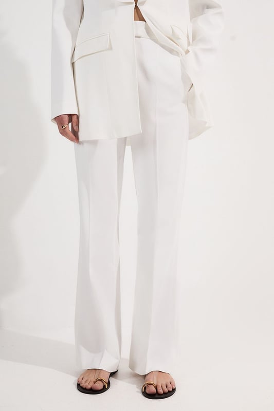These Karen Millen tailored kick flare trousers present the perfect balance of contemporary style and classic workwear sophistication. The high-rise waistband creates a flattering shape that elongates the legs, while the subtle flare adds a modern twist to traditional office attire. Style them with a fitted button-front vest and coordinating blazer for a powerful suited look, or pair them with a crisp cotton shirt and court shoes for everyday elegance. The versatile design transitions seamlessly from important meetings to after-work gatherings, simply swap your structured tote for a clutch and add statement jewellery.  Tailored high-waisted design Kick flare shape Clean, minimalist styling Viscose-blend fabric