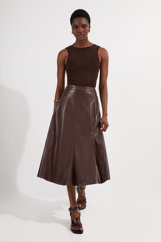 This Karen Millen faux leather midi skirt combines timeless elegance with contemporary edge. The full silhouette creates a dramatic swish with every step, while the high waistline accentuates your natural curves. Style with a fitted top for a balanced silhouette that highlights the skirt's voluminous design. For casual gatherings, pair it with a simple knit jumper and ankle boots, or dress it up with a crisp blouse and block heels for dinner dates. The versatile midi length works with both flats and heels, making this piece adaptable for family gatherings or weekend brunches. Add a cropped jacket and statement jewellery to transform this skirt into an ensemble that transitions effortlessly from day to evening wear.  Faux leather midi skirt with a full, flowing silhouette High-waisted design Elegant pleating detail Midi length Smooth finish with a subtle sheen