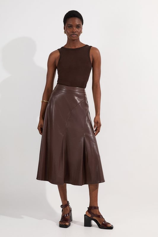 This Karen Millen faux leather midi skirt combines timeless elegance with contemporary edge. The full silhouette creates a dramatic swish with every step, while the high waistline accentuates your natural curves. Style with a fitted top for a balanced silhouette that highlights the skirt's voluminous design. For casual gatherings, pair it with a simple knit jumper and ankle boots, or dress it up with a crisp blouse and block heels for dinner dates. The versatile midi length works with both flats and heels, making this piece adaptable for family gatherings or weekend brunches. Add a cropped jacket and statement jewellery to transform this skirt into an ensemble that transitions effortlessly from day to evening wear.  Faux leather midi skirt with a full, flowing silhouette High-waisted design Elegant pleating detail Midi length Smooth finish with a subtle sheen