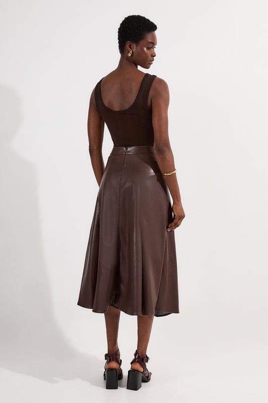 This Karen Millen faux leather midi skirt combines timeless elegance with contemporary edge. The full silhouette creates a dramatic swish with every step, while the high waistline accentuates your natural curves. Style with a fitted top for a balanced silhouette that highlights the skirt's voluminous design. For casual gatherings, pair it with a simple knit jumper and ankle boots, or dress it up with a crisp blouse and block heels for dinner dates. The versatile midi length works with both flats and heels, making this piece adaptable for family gatherings or weekend brunches. Add a cropped jacket and statement jewellery to transform this skirt into an ensemble that transitions effortlessly from day to evening wear.  Faux leather midi skirt with a full, flowing silhouette High-waisted design Elegant pleating detail Midi length Smooth finish with a subtle sheen