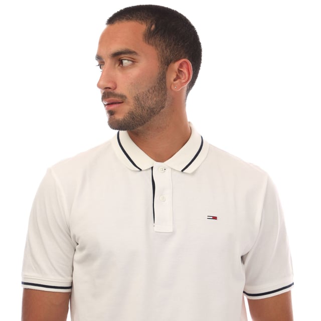 Mens Tommy Jeans Regular Fit Tipped Polo Shirt in white.- Ribbed polo collar.- Two button placket.- Short sleeves with ribbed cuffs.- Contrast tipping at collar and cuffs- Embroidered Tommy Jeans flag patch at left chest.- Even vented hem.- Soft and comfortable cotton piqué fabric  made with at least 95% regenerative cotton.- Regular fit.- 100% Cotton.  Machine washable.- Ref: DM0DM20745YBL