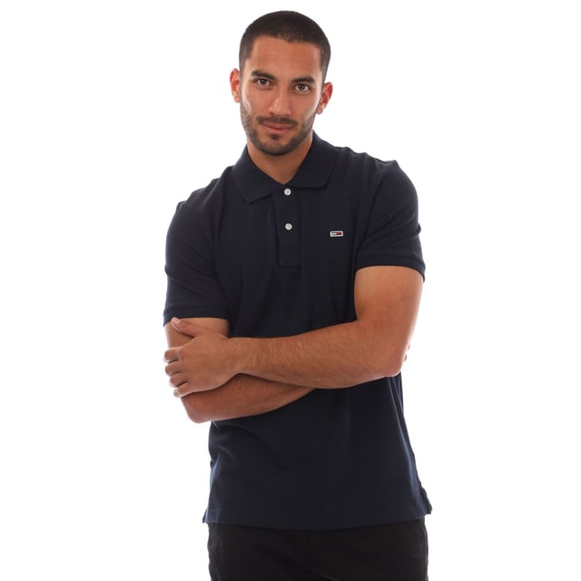 Mens Tommy Jeans Casual Polo Shirt in navy.- Ribbed polo collar.- Short sleeves with ribbed cuffs.- Two button placket.- Tommy Hilfiger flag embroidery on chest.- Split hem.- Regular fit.- 100% Cotton.- Ref.: DM0DM20763C1G