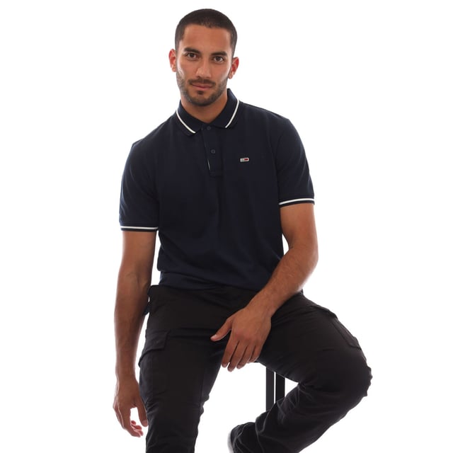 Mens Tommy Jeans Regular Fit Tipped Polo Shirt in navy.- Ribbed polo collar.- Two button placket.- Short sleeves with ribbed cuffs.- Contrast tipping at collar and cuffs- Embroidered Tommy Jeans flag patch at left chest.- Even vented hem.- Soft and comfortable cotton piqué fabric  made with at least 95% regenerative cotton.- Regular fit.- 100% Cotton.  Machine washable.- Ref: DM0DM20745C1G