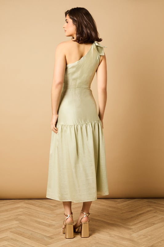 Striking one-shoulder design with an elegant oversized bow detail
        Feminine midi length with a flattering tiered skirt
        Lightweight Tencel fabric that drapes beautifully
        Clean, minimalist silhouette perfect for special occasions
        Versatile design that can be dressed up or down with accessories
    
    This enchanting one-shoulder midi dress showcases Oasis's signature feminine aesthetic with its standout bow shoulder detail. The graceful tiered skirt creates movement and dimension whilst maintaining a sophisticated silhouette. Style with strappy heeled sandals and statement earrings for summer weddings or garden parties. For race day events, pair with a fascinator and clutch bag for a refined ensemble. The versatile design transitions beautifully from daytime celebrations to evening soires-simply switch your accessories to match the occasion. The clean lines and classic shape make this dress a timeless addition to your occasion wardrobe, whilst the midi length offers both elegance and practicality. Perfect for those moments when you want to make a subtle yet memorable impression.