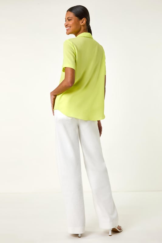 Collared Short Sleeve Blouse from Roman. Get ready to elevate your Summer wardrobe with this smart short sleeve blouse! Featuring a classic v-neckline with a trendy pyjama-style collar, this blouse is perfect for any occasion. The button front detail adds a stylish touch, while the comfortable woven fabric ensures a flattering blouse shape. Pair it with wide leg trousers and sandals for a fashionable look that exudes sophistication!