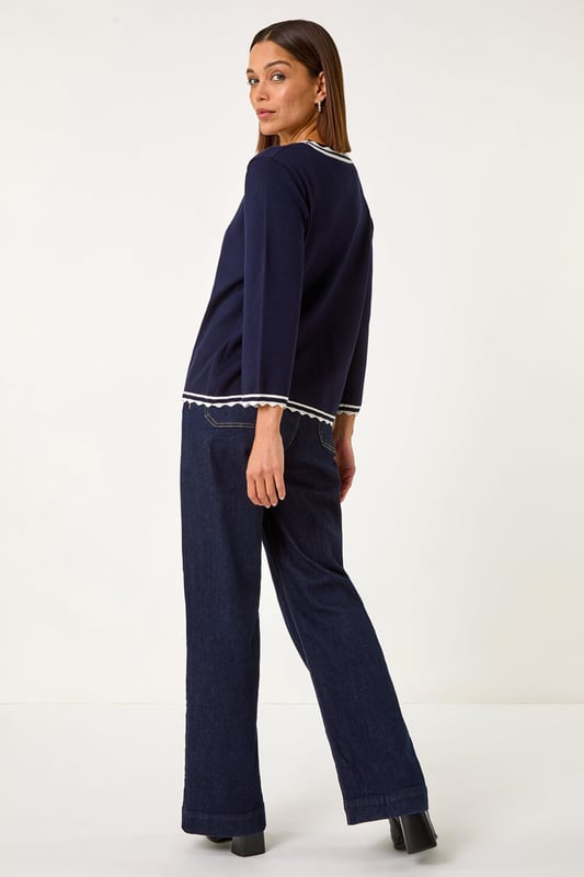 Scallop Edge Tie Cardigan from Roman. Add a touch of elegance to your Autumn/Winter wardrobe with this charming scallop edge cardigan. This lightweight piece features a unique contrast knit detail and is designed in an edge to edge style with a tie detail and delicate scallop edge. Perfect for layering, this versatile piece pairs beautifully with a simple t-shirt and jeans for a chic and polished look.
