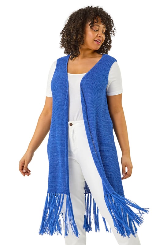 Curve Crochet Knit Tassel Cardigan from Roman. This Curve sleeveless longline cardigan features an edge to edge design with a single button fastening at the centre front for a sleek, minimalist look. The tassel hem adds a playful, boho touch, while the crochet knit fabric gives it a relaxed, textured feel. Pair it with a simple t-shirt and jeans for a casual yet stylish outfit that's perfect for layering on cooler days!