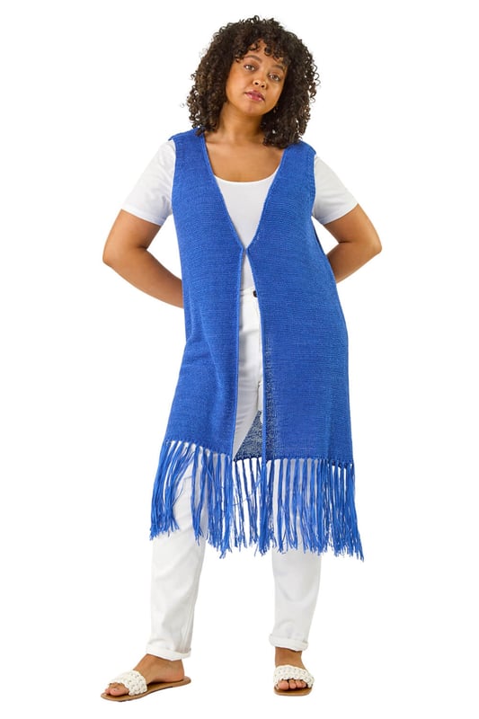 Curve Crochet Knit Tassel Cardigan from Roman. This Curve sleeveless longline cardigan features an edge to edge design with a single button fastening at the centre front for a sleek, minimalist look. The tassel hem adds a playful, boho touch, while the crochet knit fabric gives it a relaxed, textured feel. Pair it with a simple t-shirt and jeans for a casual yet stylish outfit that's perfect for layering on cooler days!