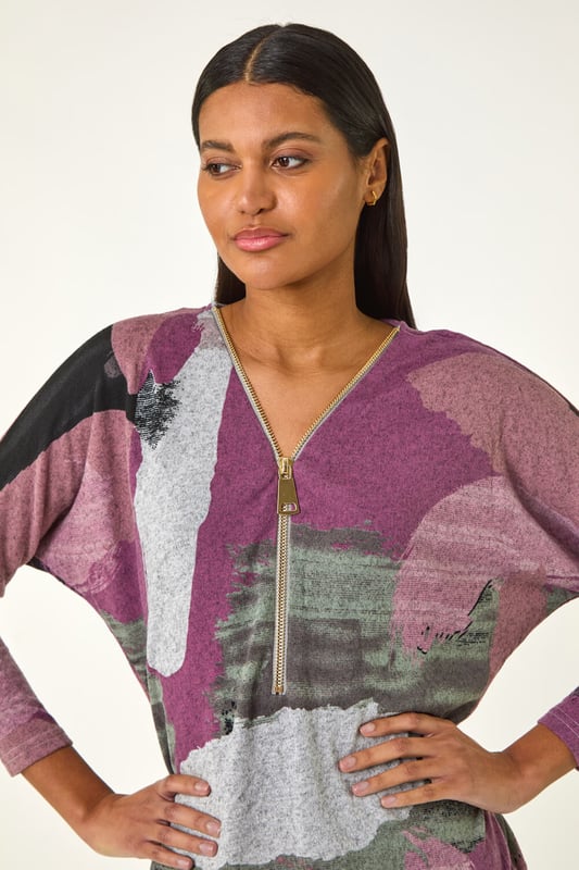 Brushed Print Zip Detail Top from Roman. Stay stylish and on trend this Autumn/Winter season with this vibrant brushed zip top. Featuring an eye catching all over abstract print, this top boasts a sleek zip front and a flattering V-Neck design. Complete with chic long sleeves and a modern silver zip detail for added flair. Pair with jeggings and ankle boots for a fashionable and comfortable look.