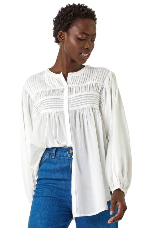 Pleat Detail Button Through Blouse from Roman. Add a touch of sophistication to your wardrobe with this pleat detail button-through blouse. Crafted from a soft cotton fabric, this classic round neckline design features long sleeves to keep you warm during the Autumn Winter. Complete with stylish front pleat detail and trendy button-through opening, this blouse adds a subtle elegance to your outfit. Style effortlessly with jeggings and ankle boots for a complete fall look!