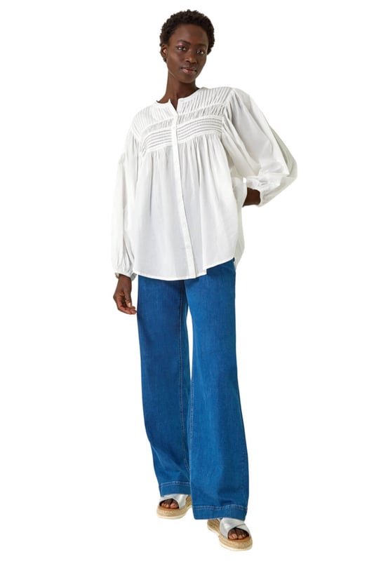 Pleat Detail Button Through Blouse from Roman. Add a touch of sophistication to your wardrobe with this pleat detail button-through blouse. Crafted from a soft cotton fabric, this classic round neckline design features long sleeves to keep you warm during the Autumn Winter. Complete with stylish front pleat detail and trendy button-through opening, this blouse adds a subtle elegance to your outfit. Style effortlessly with jeggings and ankle boots for a complete fall look!