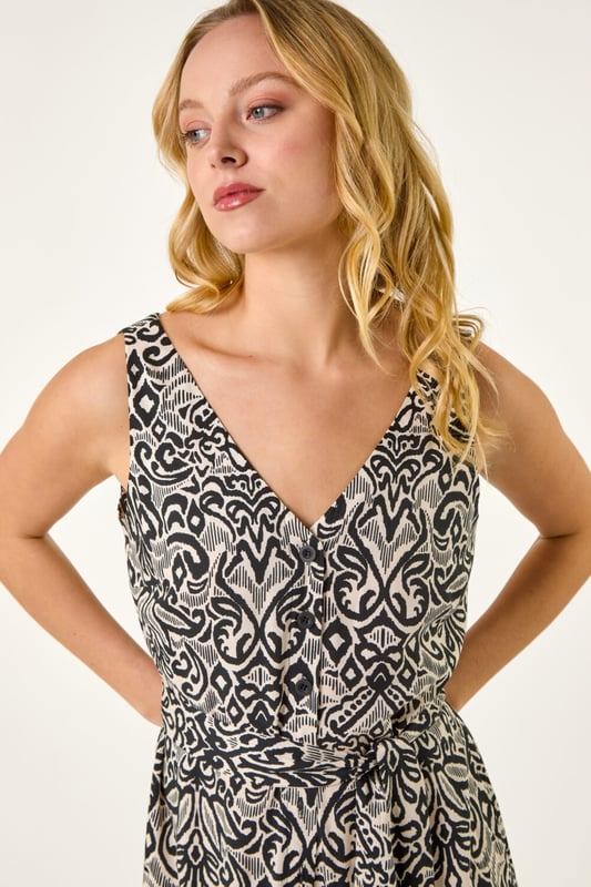 Dusk Abstract Print Jumpsuit from Roman. Effortlessly chic and perfect for the warmer months, this abstract jumpsuit is a must-have for your Spring/Summer wardrobe. Featuring a flattering v-neckline and stylish sleeveless design, this jumpsuit is the epitome of easy elegance. Pair it with sandals and a denim jacket for a laid-back yet sophisticated look that will take you from day to night with ease.