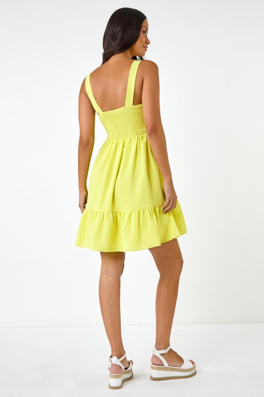 Dusk Poplin Tiered Swing Dress from Roman. Unleash your inner fashionista with this trendy tiered swing dress, perfect for the Spring Summer season. Crafted from a soft poplin woven fabric, this knee length beauty features a classic square neckline and sleeveless style. The swing shape and tiered skirt add a touch of fun to your outfit, ensuring you stand out in style. Pair with a cardigan and wedge heels for a complete look!