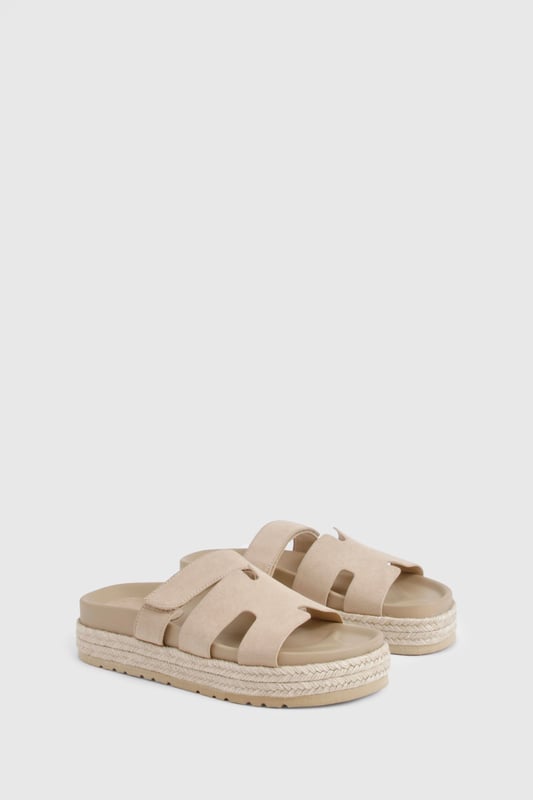 Faux suede slides with distinctive cut-out strap design for breathability
        Flatform espadrille-style sole with textured detailing for added grip
        Flat heel height (0-2cm) offering all-day comfort without sacrificing style
        Cushioned footbed providing essential support for extended wear
        Adjustable strap with buckle fastening for a customisable fit
    
    These versatile slides combine casual charm with practical design, perfect for effortless summer styling. The flatform espadrille-inspired sole adds subtle height whilst maintaining walkability, making them ideal for everything from beach days to city strolls. Pair with frayed denim shorts and an oversized linen shirt for a relaxed daytime look, or style with a flowing maxi dress for casual garden parties. The neutral finish ensures these slides will complement virtually any outfit in your warm-weather wardrobe. Their cushioned construction means you can comfortably wear them all day, whether you're running errands or meeting friends for brunch. A true summer essential that balances fashion-forward design with everyday functionality - the ultimate footwear solution for the girl who values both style and comfort.