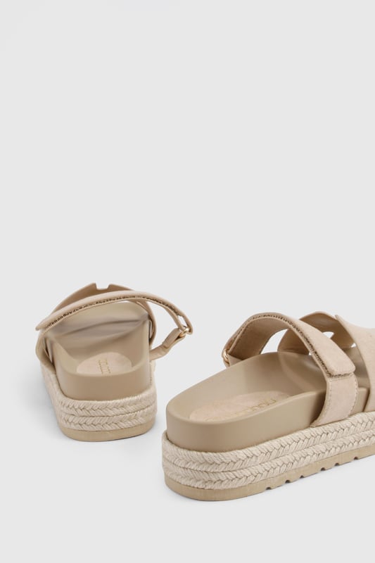 Faux suede slides with distinctive cut-out strap design for breathability
        Flatform espadrille-style sole with textured detailing for added grip
        Flat heel height (0-2cm) offering all-day comfort without sacrificing style
        Cushioned footbed providing essential support for extended wear
        Adjustable strap with buckle fastening for a customisable fit
    
    These versatile slides combine casual charm with practical design, perfect for effortless summer styling. The flatform espadrille-inspired sole adds subtle height whilst maintaining walkability, making them ideal for everything from beach days to city strolls. Pair with frayed denim shorts and an oversized linen shirt for a relaxed daytime look, or style with a flowing maxi dress for casual garden parties. The neutral finish ensures these slides will complement virtually any outfit in your warm-weather wardrobe. Their cushioned construction means you can comfortably wear them all day, whether you're running errands or meeting friends for brunch. A true summer essential that balances fashion-forward design with everyday functionality - the ultimate footwear solution for the girl who values both style and comfort.