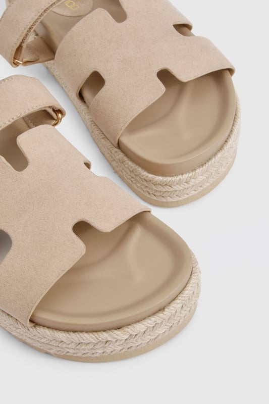 Faux suede slides with distinctive cut-out strap design for breathability
        Flatform espadrille-style sole with textured detailing for added grip
        Flat heel height (0-2cm) offering all-day comfort without sacrificing style
        Cushioned footbed providing essential support for extended wear
        Adjustable strap with buckle fastening for a customisable fit
    
    These versatile slides combine casual charm with practical design, perfect for effortless summer styling. The flatform espadrille-inspired sole adds subtle height whilst maintaining walkability, making them ideal for everything from beach days to city strolls. Pair with frayed denim shorts and an oversized linen shirt for a relaxed daytime look, or style with a flowing maxi dress for casual garden parties. The neutral finish ensures these slides will complement virtually any outfit in your warm-weather wardrobe. Their cushioned construction means you can comfortably wear them all day, whether you're running errands or meeting friends for brunch. A true summer essential that balances fashion-forward design with everyday functionality - the ultimate footwear solution for the girl who values both style and comfort.