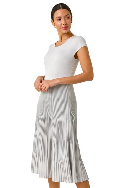 Shimmer Knit Pleated Dress from Roman. Shine bright in this silver knitted dress perfect for the warmer months. Designed with a pleated skirt and cut from a soft knitted fabric, this dress features an elasticated waistband for comfort. With a zipless, over head design, it offers easy wearability and a flattering fit. Pair with strappy heels and a blazer for an elegant and stylish look that's sure to turn heads this Spring/Summer!