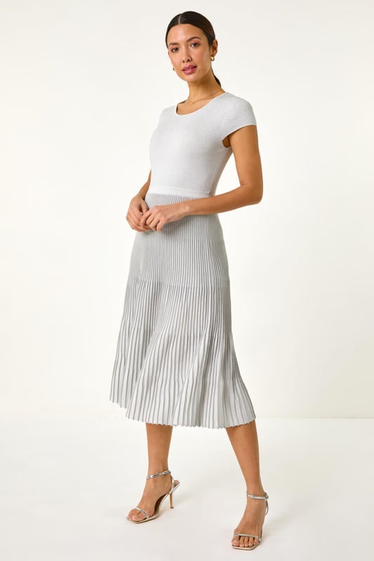 Shimmer Knit Pleated Dress from Roman. Shine bright in this silver knitted dress perfect for the warmer months. Designed with a pleated skirt and cut from a soft knitted fabric, this dress features an elasticated waistband for comfort. With a zipless, over head design, it offers easy wearability and a flattering fit. Pair with strappy heels and a blazer for an elegant and stylish look that's sure to turn heads this Spring/Summer!