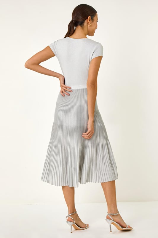 Shimmer Knit Pleated Dress from Roman. Shine bright in this silver knitted dress perfect for the warmer months. Designed with a pleated skirt and cut from a soft knitted fabric, this dress features an elasticated waistband for comfort. With a zipless, over head design, it offers easy wearability and a flattering fit. Pair with strappy heels and a blazer for an elegant and stylish look that's sure to turn heads this Spring/Summer!