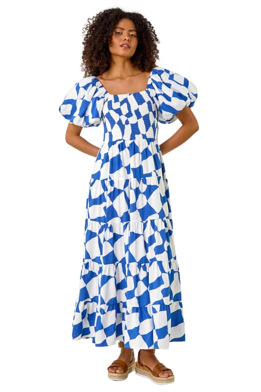 Dusk Geo Print Tiered Dress from Roman. Feel effortless this Spring Summer season with our Dusk tiered geo print dress. This trendy dress features a square neckline and playful short puff sleeves, adding a fun touch to your outfit. Cut and lined with a comfortable woven fabric, the dress boasts a flattering shirred bodice and a midi length tiered skirt, ensuring all-day comfort. Style with a denim jacket and wedge heels for the perfect look you'll love!