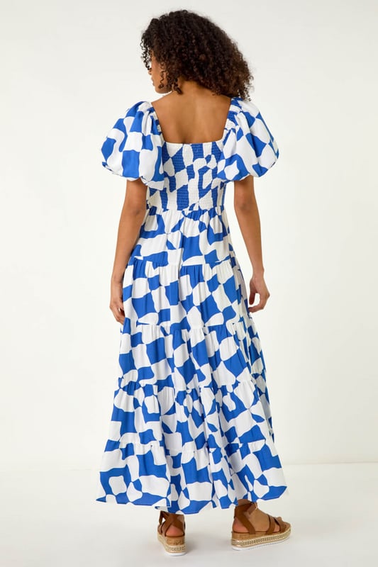 Dusk Geo Print Tiered Dress from Roman. Feel effortless this Spring Summer season with our Dusk tiered geo print dress. This trendy dress features a square neckline and playful short puff sleeves, adding a fun touch to your outfit. Cut and lined with a comfortable woven fabric, the dress boasts a flattering shirred bodice and a midi length tiered skirt, ensuring all-day comfort. Style with a denim jacket and wedge heels for the perfect look you'll love!