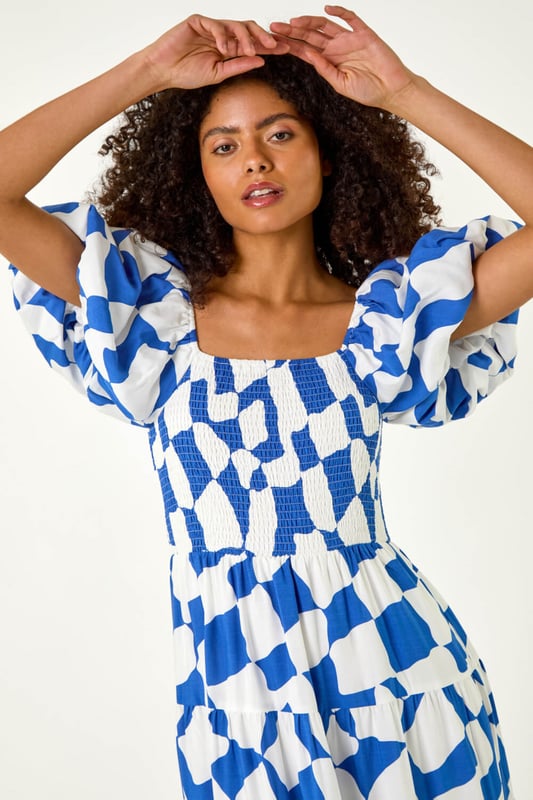 Dusk Geo Print Tiered Dress from Roman. Feel effortless this Spring Summer season with our Dusk tiered geo print dress. This trendy dress features a square neckline and playful short puff sleeves, adding a fun touch to your outfit. Cut and lined with a comfortable woven fabric, the dress boasts a flattering shirred bodice and a midi length tiered skirt, ensuring all-day comfort. Style with a denim jacket and wedge heels for the perfect look you'll love!