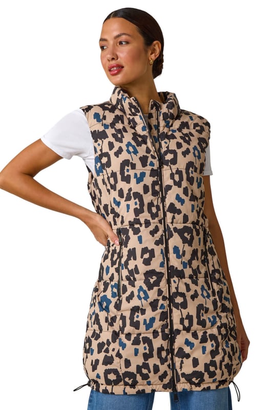 Animal Print Hooded Gilet from Roman. Stay stylish and on-trend this Spring Summer with this animal print hooded gilet in a longline silhouette. The eye-catching animal print adds a wild twist to this quilted piece, featuring a zip and practical zip pockets at the front. The gilet boasts a cosy funnel neck and a drawcord hood. Layer it over your favourite shirt and jeggings for a fashionable look that's versatile and perfect for the season!