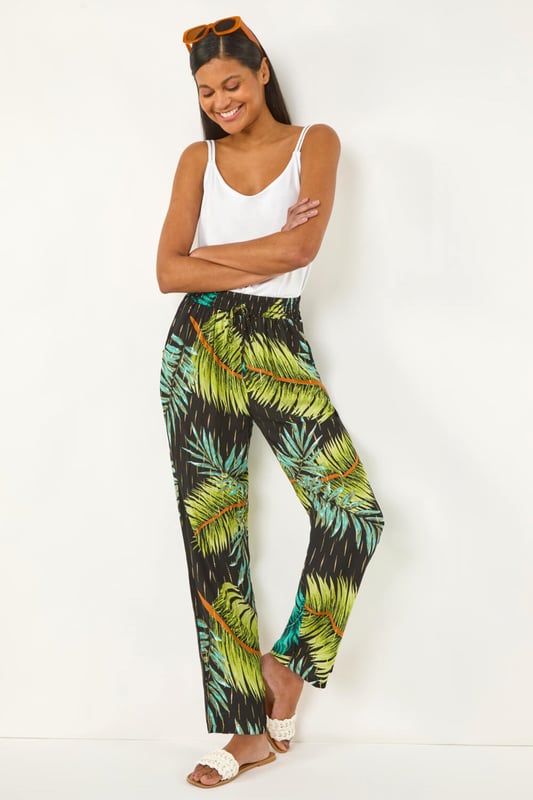 Shimmer Palm Print Harem Trouser from Roman. Elevate your wardrobe with these stylish palm shimmer harem trousers, designed for both comfort and elegance. Featuring a flattering elasticated waist with an adjustable drawcord, they offer a perfect fit while the lightweight, flowy fabric adds effortless movement. Ideal for warm-weather days and holiday escapes, pair them with a cami top and sandals for an effortlessly chic look.