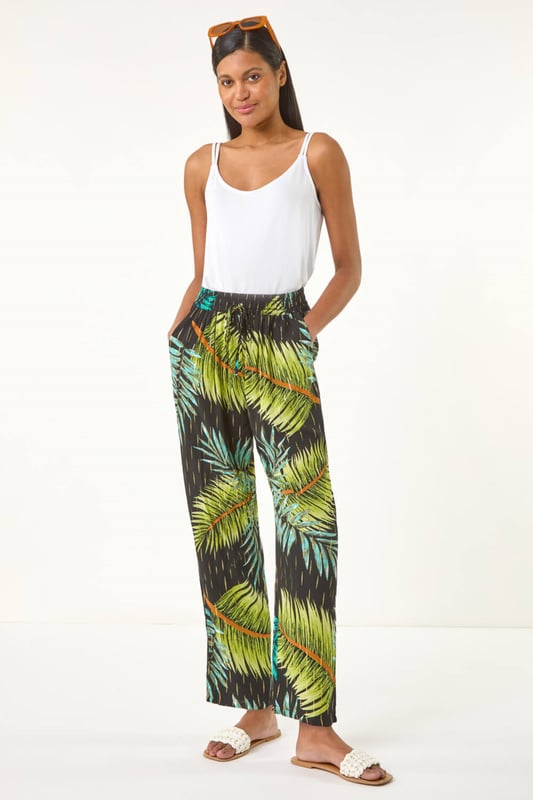 Shimmer Palm Print Harem Trouser from Roman. Elevate your wardrobe with these stylish palm shimmer harem trousers, designed for both comfort and elegance. Featuring a flattering elasticated waist with an adjustable drawcord, they offer a perfect fit while the lightweight, flowy fabric adds effortless movement. Ideal for warm-weather days and holiday escapes, pair them with a cami top and sandals for an effortlessly chic look.