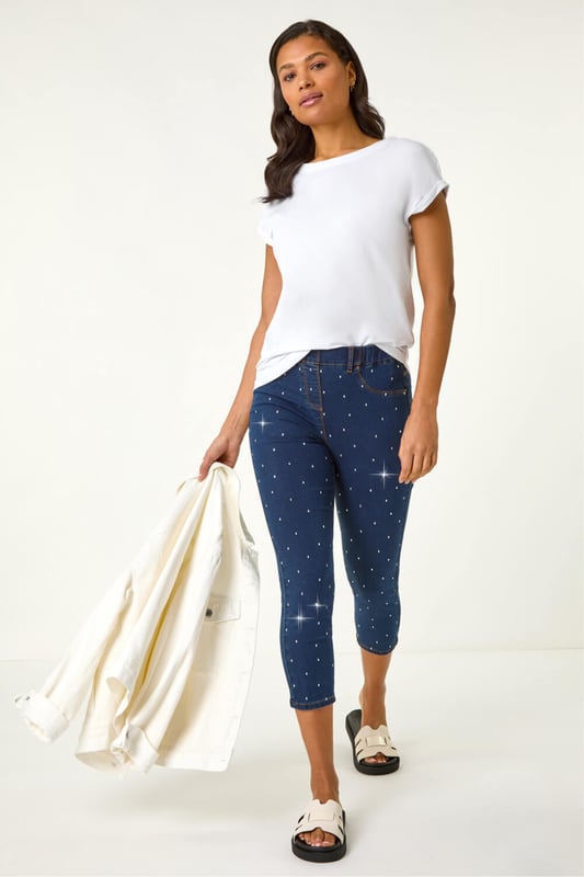 Embellished Cropped Stretch Jeggings from Roman. Get ready to sparkle in these cropped jeggings this Spring Summer! Featuring functional belt loops and a flattering shape, these denim jeggings are adorned with beautiful embellished details. Cut from a soft, stretch cotton fabric, they finish at a stylish cropped length. Pair with a white blouse and wedge sandals for a trendy outfit that effortlessly transitions from day to night.