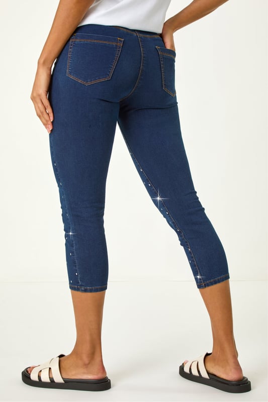 Embellished Cropped Stretch Jeggings from Roman. Get ready to sparkle in these cropped jeggings this Spring Summer! Featuring functional belt loops and a flattering shape, these denim jeggings are adorned with beautiful embellished details. Cut from a soft, stretch cotton fabric, they finish at a stylish cropped length. Pair with a white blouse and wedge sandals for a trendy outfit that effortlessly transitions from day to night.