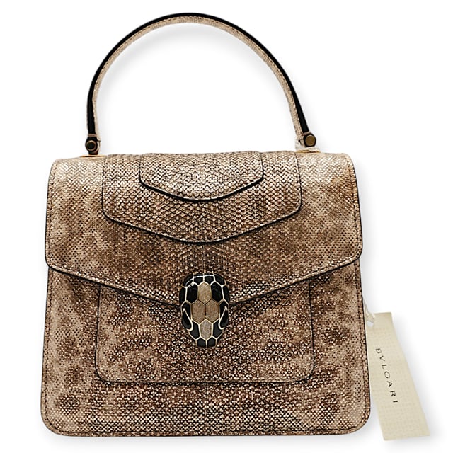 Die kleine Serpenti Forever Henkeltasche besticht durch exquisite Handwerkskunst. Ihr handgefertigter und sorgfältig bemalter Korpus besteht aus luxuriösem, silberfarbenem Karung-Leder mit Perlenbesatz. Diese elegante Kreation vereint edle Materialien nahtlos mit praktischer Vielseitigkeit und besticht durch eine markante Kette in Schlangenform und einen Lederriemen. Der ikonische Magnetverschluss in Schlangenkopfform, inspiriert vom Serpenti-Schmuck der 1960er Jahre, verleiht mit seinem filigranen Schuppendesign einen faszinierenden Touch. Die Tasche ist durchdacht gestaltet und verfügt über drei Fächer: ein aufgesetztes Gesäßfach, ein offenes Innenfach, ein spezielles Spiegelfach mit einem individualisierbaren Spiegel, ein inneres Metalletikett mit dem Bvlgari-Logo und das charakteristische Bvlgari-Metalllogo auf der Rückseite.

Lieferumfang: Regenschutz, Staubbeutel, Echtheitszertifikat, Riemen, kleiner Spiegel
Anmerkungen: Insgesamt keine Beschädigungen
NFT-Option verfügbar. Mehr erfahren.
Gesicherte Produktauthentizität: Dieses Produkt wird von einem renommierten und vertrauenswürdigen Partner geliefert.
Mit diesem Kauf bewahren Sie ikonische Handwerkskunst, feiern das Erbe und genießen die Schönheit des bewussten Einkaufens. Maße: Breite: 228 mm Länge: 482 mm Höhe: 425 mm Riemenlänge: 1050 mm Griffabfall: 584,2 mm