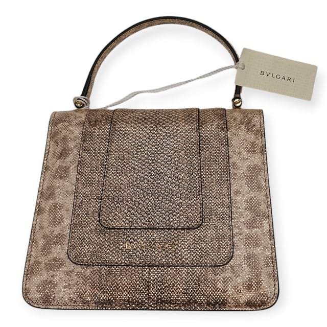 Die kleine Serpenti Forever Henkeltasche besticht durch exquisite Handwerkskunst. Ihr handgefertigter und sorgfältig bemalter Korpus besteht aus luxuriösem, silberfarbenem Karung-Leder mit Perlenbesatz. Diese elegante Kreation vereint edle Materialien nahtlos mit praktischer Vielseitigkeit und besticht durch eine markante Kette in Schlangenform und einen Lederriemen. Der ikonische Magnetverschluss in Schlangenkopfform, inspiriert vom Serpenti-Schmuck der 1960er Jahre, verleiht mit seinem filigranen Schuppendesign einen faszinierenden Touch. Die Tasche ist durchdacht gestaltet und verfügt über drei Fächer: ein aufgesetztes Gesäßfach, ein offenes Innenfach, ein spezielles Spiegelfach mit einem individualisierbaren Spiegel, ein inneres Metalletikett mit dem Bvlgari-Logo und das charakteristische Bvlgari-Metalllogo auf der Rückseite.

Lieferumfang: Regenschutz, Staubbeutel, Echtheitszertifikat, Riemen, kleiner Spiegel
Anmerkungen: Insgesamt keine Beschädigungen
NFT-Option verfügbar. Mehr erfahren.
Gesicherte Produktauthentizität: Dieses Produkt wird von einem renommierten und vertrauenswürdigen Partner geliefert.
Mit diesem Kauf bewahren Sie ikonische Handwerkskunst, feiern das Erbe und genießen die Schönheit des bewussten Einkaufens. Maße: Breite: 228 mm Länge: 482 mm Höhe: 425 mm Riemenlänge: 1050 mm Griffabfall: 584,2 mm