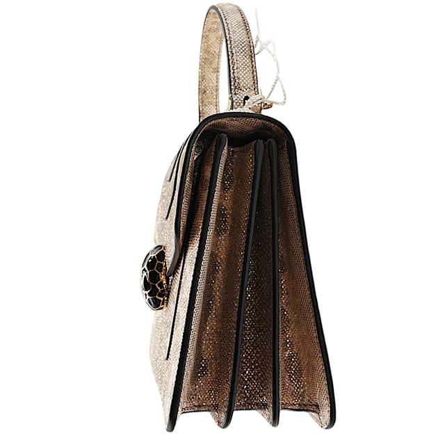 Die kleine Serpenti Forever Henkeltasche besticht durch exquisite Handwerkskunst. Ihr handgefertigter und sorgfältig bemalter Korpus besteht aus luxuriösem, silberfarbenem Karung-Leder mit Perlenbesatz. Diese elegante Kreation vereint edle Materialien nahtlos mit praktischer Vielseitigkeit und besticht durch eine markante Kette in Schlangenform und einen Lederriemen. Der ikonische Magnetverschluss in Schlangenkopfform, inspiriert vom Serpenti-Schmuck der 1960er Jahre, verleiht mit seinem filigranen Schuppendesign einen faszinierenden Touch. Die Tasche ist durchdacht gestaltet und verfügt über drei Fächer: ein aufgesetztes Gesäßfach, ein offenes Innenfach, ein spezielles Spiegelfach mit einem individualisierbaren Spiegel, ein inneres Metalletikett mit dem Bvlgari-Logo und das charakteristische Bvlgari-Metalllogo auf der Rückseite.

Lieferumfang: Regenschutz, Staubbeutel, Echtheitszertifikat, Riemen, kleiner Spiegel
Anmerkungen: Insgesamt keine Beschädigungen
NFT-Option verfügbar. Mehr erfahren.
Gesicherte Produktauthentizität: Dieses Produkt wird von einem renommierten und vertrauenswürdigen Partner geliefert.
Mit diesem Kauf bewahren Sie ikonische Handwerkskunst, feiern das Erbe und genießen die Schönheit des bewussten Einkaufens. Maße: Breite: 228 mm Länge: 482 mm Höhe: 425 mm Riemenlänge: 1050 mm Griffabfall: 584,2 mm