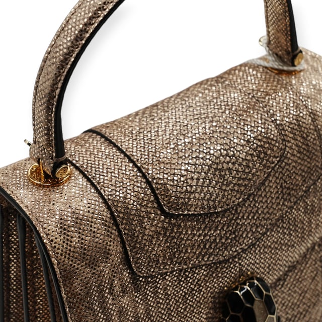 Die kleine Serpenti Forever Henkeltasche besticht durch exquisite Handwerkskunst. Ihr handgefertigter und sorgfältig bemalter Korpus besteht aus luxuriösem, silberfarbenem Karung-Leder mit Perlenbesatz. Diese elegante Kreation vereint edle Materialien nahtlos mit praktischer Vielseitigkeit und besticht durch eine markante Kette in Schlangenform und einen Lederriemen. Der ikonische Magnetverschluss in Schlangenkopfform, inspiriert vom Serpenti-Schmuck der 1960er Jahre, verleiht mit seinem filigranen Schuppendesign einen faszinierenden Touch. Die Tasche ist durchdacht gestaltet und verfügt über drei Fächer: ein aufgesetztes Gesäßfach, ein offenes Innenfach, ein spezielles Spiegelfach mit einem individualisierbaren Spiegel, ein inneres Metalletikett mit dem Bvlgari-Logo und das charakteristische Bvlgari-Metalllogo auf der Rückseite.

Lieferumfang: Regenschutz, Staubbeutel, Echtheitszertifikat, Riemen, kleiner Spiegel
Anmerkungen: Insgesamt keine Beschädigungen
NFT-Option verfügbar. Mehr erfahren.
Gesicherte Produktauthentizität: Dieses Produkt wird von einem renommierten und vertrauenswürdigen Partner geliefert.
Mit diesem Kauf bewahren Sie ikonische Handwerkskunst, feiern das Erbe und genießen die Schönheit des bewussten Einkaufens. Maße: Breite: 228 mm Länge: 482 mm Höhe: 425 mm Riemenlänge: 1050 mm Griffabfall: 584,2 mm