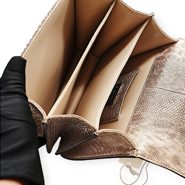 Die kleine Serpenti Forever Henkeltasche besticht durch exquisite Handwerkskunst. Ihr handgefertigter und sorgfältig bemalter Korpus besteht aus luxuriösem, silberfarbenem Karung-Leder mit Perlenbesatz. Diese elegante Kreation vereint edle Materialien nahtlos mit praktischer Vielseitigkeit und besticht durch eine markante Kette in Schlangenform und einen Lederriemen. Der ikonische Magnetverschluss in Schlangenkopfform, inspiriert vom Serpenti-Schmuck der 1960er Jahre, verleiht mit seinem filigranen Schuppendesign einen faszinierenden Touch. Die Tasche ist durchdacht gestaltet und verfügt über drei Fächer: ein aufgesetztes Gesäßfach, ein offenes Innenfach, ein spezielles Spiegelfach mit einem individualisierbaren Spiegel, ein inneres Metalletikett mit dem Bvlgari-Logo und das charakteristische Bvlgari-Metalllogo auf der Rückseite.

Lieferumfang: Regenschutz, Staubbeutel, Echtheitszertifikat, Riemen, kleiner Spiegel
Anmerkungen: Insgesamt keine Beschädigungen
NFT-Option verfügbar. Mehr erfahren.
Gesicherte Produktauthentizität: Dieses Produkt wird von einem renommierten und vertrauenswürdigen Partner geliefert.
Mit diesem Kauf bewahren Sie ikonische Handwerkskunst, feiern das Erbe und genießen die Schönheit des bewussten Einkaufens. Maße: Breite: 228 mm Länge: 482 mm Höhe: 425 mm Riemenlänge: 1050 mm Griffabfall: 584,2 mm