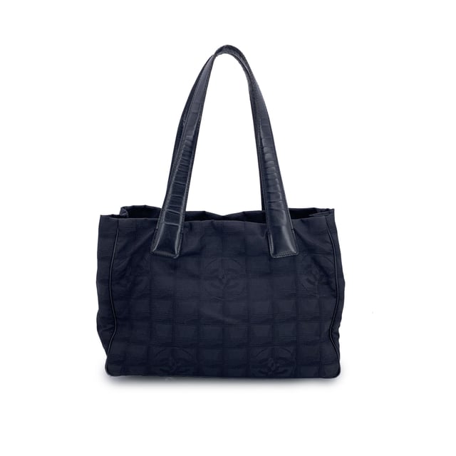 VINTAGE, RRP AS NEW
Chanel Travel Line Tote (2003-2004) - Understated Elegance in Motion  Timeless, functional, and distinctly Chanel - this black jacquard nylon tote from the house's Travel Line collection is a minimalist masterpiece from the 2003-2004 era, designed with the modern voyager in mind.  Crafted from sleek black jacquard nylon, the bag features the iconic Chanel motif subtly woven into the fabric - a quiet nod to the maison's storied heritage. The silhouette is elevated by a black leather shoulder straps/handles, offering both comfort and sophistication for life on the move.  Inside, the nylon lining holds two side zip pockets, perfect for keeping essentials within reach while maintaining the tote's clean lines. True to Chanel's legacy of craftsmanship, the interior bears the 'Chanel - Made in Italy' tag and a discreet ity hologram, grounding this vintage gem in ity and history.  Effortlessly chic and endlessly versatile, this Chanel Travel Line tote is a sophisticated companion - ideal for everyday elegance, city strolls, or quiet getaways. A rare find for collectors and lovers of early-2000s Chanel. Condition Rating: B - VERY GOOD CONDITIONCondition Details: Some wear of use on bottom corners. Some normal wear of use on leather handles. Please, look carefully at the photos and ask if you have any doubts.Measurements (cm):Depth: 11.4Height: 20.3Length: 27.9Other Details: Dustbag? NoKeys? NoBox? No Measurments:  width: 114 mm length: 279 mm height: 203 mm