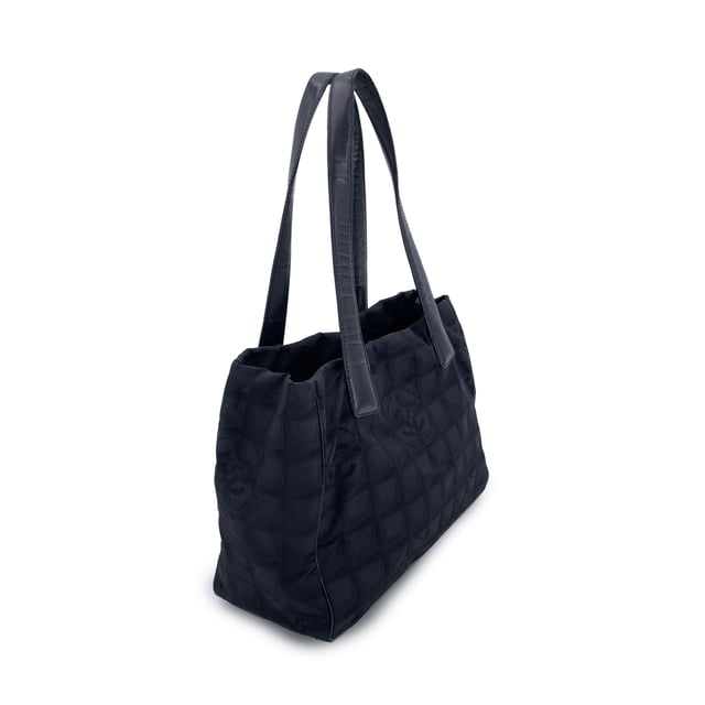 VINTAGE, RRP AS NEW
Chanel Travel Line Tote (2003-2004) - Understated Elegance in Motion  Timeless, functional, and distinctly Chanel - this black jacquard nylon tote from the house's Travel Line collection is a minimalist masterpiece from the 2003-2004 era, designed with the modern voyager in mind.  Crafted from sleek black jacquard nylon, the bag features the iconic Chanel motif subtly woven into the fabric - a quiet nod to the maison's storied heritage. The silhouette is elevated by a black leather shoulder straps/handles, offering both comfort and sophistication for life on the move.  Inside, the nylon lining holds two side zip pockets, perfect for keeping essentials within reach while maintaining the tote's clean lines. True to Chanel's legacy of craftsmanship, the interior bears the 'Chanel - Made in Italy' tag and a discreet ity hologram, grounding this vintage gem in ity and history.  Effortlessly chic and endlessly versatile, this Chanel Travel Line tote is a sophisticated companion - ideal for everyday elegance, city strolls, or quiet getaways. A rare find for collectors and lovers of early-2000s Chanel. Condition Rating: B - VERY GOOD CONDITIONCondition Details: Some wear of use on bottom corners. Some normal wear of use on leather handles. Please, look carefully at the photos and ask if you have any doubts.Measurements (cm):Depth: 11.4Height: 20.3Length: 27.9Other Details: Dustbag? NoKeys? NoBox? No Measurments:  width: 114 mm length: 279 mm height: 203 mm