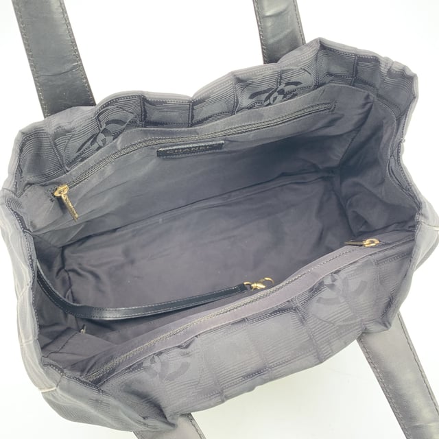 VINTAGE, RRP AS NEW
Chanel Travel Line Tote (2003-2004) - Understated Elegance in Motion  Timeless, functional, and distinctly Chanel - this black jacquard nylon tote from the house's Travel Line collection is a minimalist masterpiece from the 2003-2004 era, designed with the modern voyager in mind.  Crafted from sleek black jacquard nylon, the bag features the iconic Chanel motif subtly woven into the fabric - a quiet nod to the maison's storied heritage. The silhouette is elevated by a black leather shoulder straps/handles, offering both comfort and sophistication for life on the move.  Inside, the nylon lining holds two side zip pockets, perfect for keeping essentials within reach while maintaining the tote's clean lines. True to Chanel's legacy of craftsmanship, the interior bears the 'Chanel - Made in Italy' tag and a discreet ity hologram, grounding this vintage gem in ity and history.  Effortlessly chic and endlessly versatile, this Chanel Travel Line tote is a sophisticated companion - ideal for everyday elegance, city strolls, or quiet getaways. A rare find for collectors and lovers of early-2000s Chanel. Condition Rating: B - VERY GOOD CONDITIONCondition Details: Some wear of use on bottom corners. Some normal wear of use on leather handles. Please, look carefully at the photos and ask if you have any doubts.Measurements (cm):Depth: 11.4Height: 20.3Length: 27.9Other Details: Dustbag? NoKeys? NoBox? No Measurments:  width: 114 mm length: 279 mm height: 203 mm