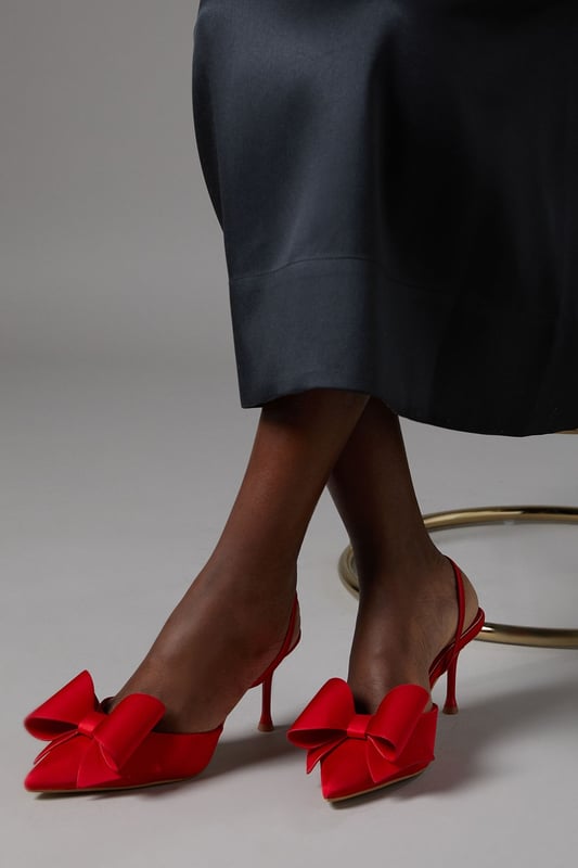Elegant satin court shoes with a striking bow detail
        Slingback design for a secure and comfortable fit
        Medium stiletto heel measuring between 5 and 6.5cm
        Pointed toe silhouette for a sophisticated look
        Versatile style suitable for various formal occasions
    
    Step into elegance with these exquisite Lola satin court shoes from Coast. The eye-catching bow detail adorning the pointed toe adds a touch of feminine charm, while the slingback design ensures a secure fit as you glide across the dance floor. With a medium stiletto heel that strikes the perfect balance between comfort and style, these shoes are ideal for weddings, race days, or any sophisticated soire. Pair them with a flowing midi dress for a timeless ensemble, or contrast their delicate appearance with a sharply tailored suit for a modern twist. The versatility of these shoes makes them a wardrobe staple for the discerning woman who appreciates quality and style in equal measure.