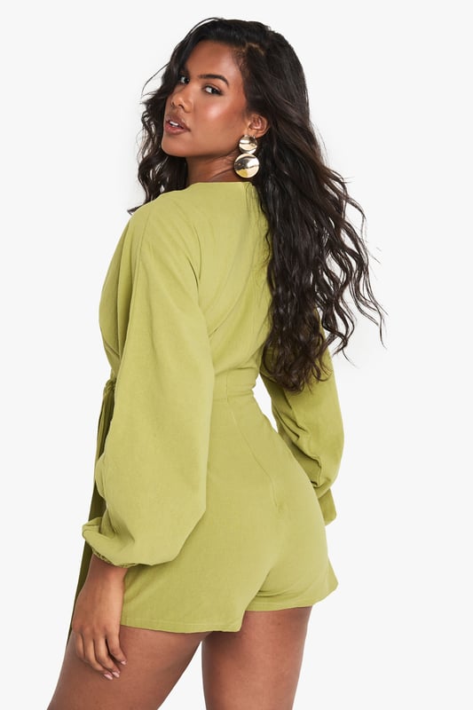 Wrap-over design with tie detail for adjustable fit
        Flattering V-neckline
        Voluminous balloon sleeves for dramatic flair
        Linen-look fabric for a breezy, textured appearance
        Versatile playsuit suitable for various casual occasions
    
    Embrace effortless chic with this wrap-over tie detail playsuit from Boohoo. The linen-look fabric offers a lightweight feel, perfect for warm-weather outings. Its striking balloon sleeves add a touch of drama to the silhouette, while the V-neckline flatters your dcolletage. Style this playsuit with strappy sandals and a woven bag for a laid-back brunch with friends. For family gatherings, pair it with white trainers and delicate gold jewellery. The adjustable tie allows you to customise the fit, making it a versatile piece for your wardrobe. Whether you're heading to a casual garden party or a day out shopping, this playsuit offers both comfort and style. Its relaxed yet put-together look makes it an ideal choice for those who want to stay on-trend without compromising on ease.