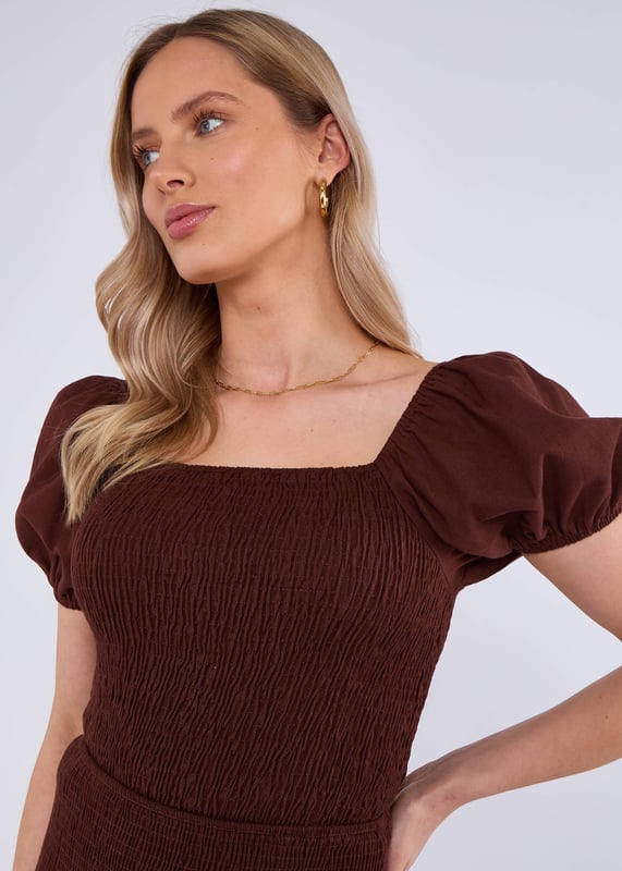 Eleva tu estilo con nuestro top de algodón con mangas abullonadas y fruncido en color chocolate. Confeccionado en lujoso algodón, el diseño fruncido y las mangas abullonadas añaden un toque de estilo a cualquier armario. Mantente cómoda y a la moda durante todo el día.