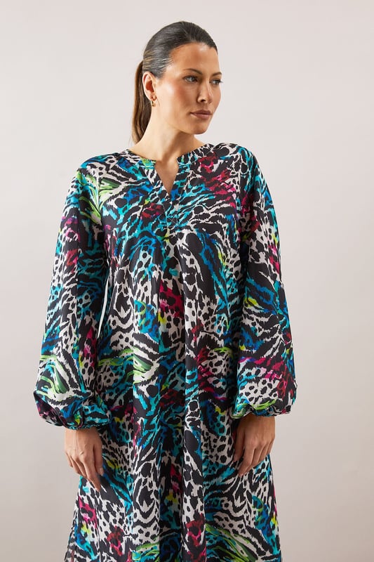 Collarless midaxi dress featuring a striking zebra print pattern with vibrant hues
        Elegant crew neckline with subtle split detail for a refined touch
        Voluminous balloon sleeves create a dramatic silhouette
        Relaxed, flowing fit through the body for all-day comfort
        Midaxi length offers versatile styling options for various occasions
    
    Make a statement with this eye-catching Wallis zebra print midaxi dress. The relaxed silhouette combines sophistication with comfort, making it perfect for daytime engagements. Style with flat sandals as shown for family gatherings or weekend brunches, or pair with a sleek ponytail and minimal jewellery for a more polished look. The balloon sleeves add a contemporary touch to this wearable piece, while the midaxi length offers flattering coverage. Layer with a cropped denim jacket for casual outings or add a structured blazer for lunch dates. This versatile dress transitions effortlessly from shopping trips to casual meet-ups with friends, embodying the sophisticated yet comfortable aesthetic that Wallis is known for.