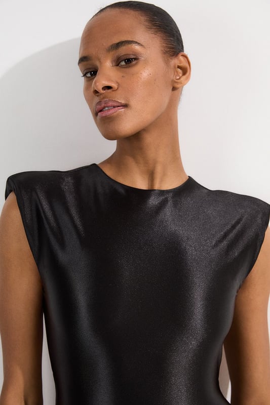 Make a statement poolside with this Wet Look Power Shoulder Cut Out Swimsuit. The architectural power shoulders create a bold, fashion-forward silhouette that commands attention, whilst the strategic cut-out detail adds intrigue to this one-piece design. Perfect for lounging by the pool at exclusive resorts or enjoying sunny beach days, this swimsuit transitions effortlessly from daytime swimming to sunset cocktails when paired with a flowing maxi skirt and statement jewellery. The sleek wet look fabric hugs your curves in all the right places, offering both style and comfort for your summer getaways.   Wet look finish catches the light. Bold power shoulder design Sleek cut-out detail Crew neckline offers coverage High-cut design elongates your figure